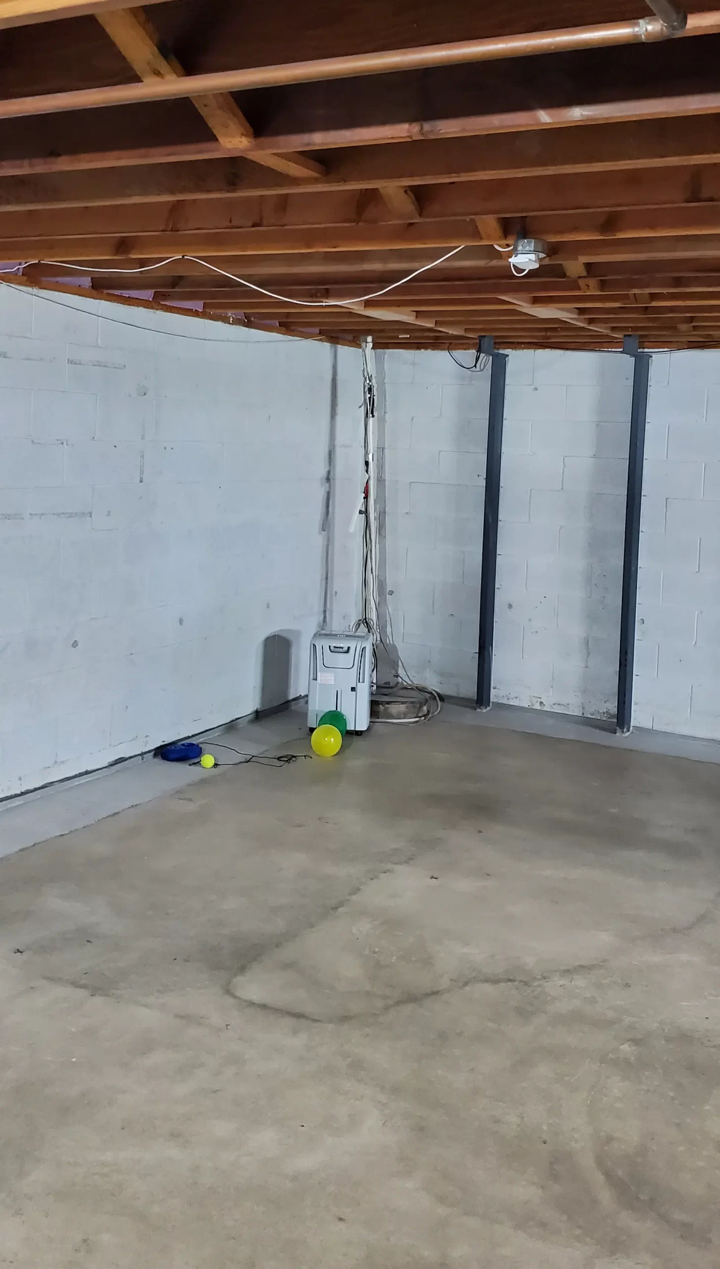 Unfinished basement with block walls, exposed joists and bare concrete floor