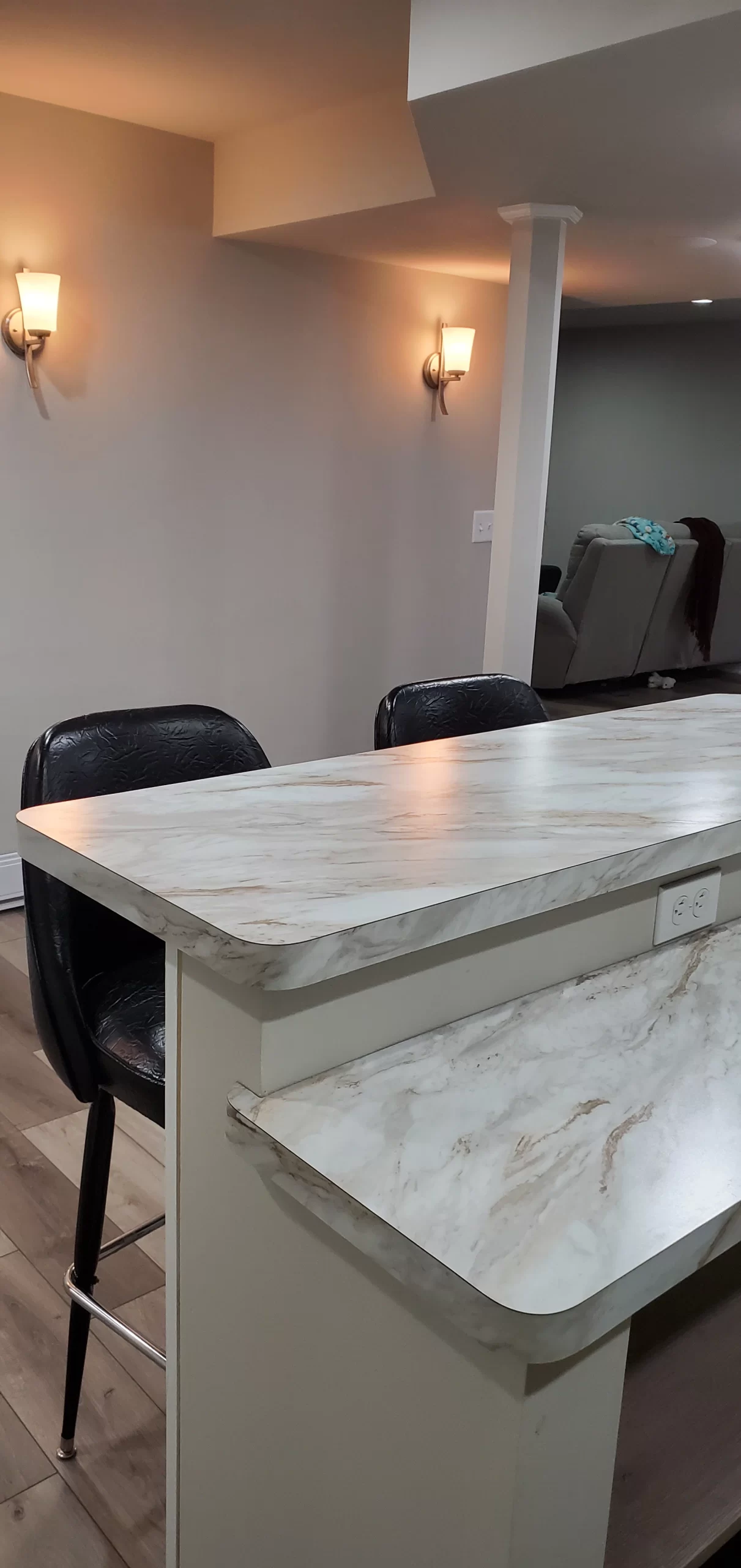 Finished basement bar with marble-look countertop and modern barstools