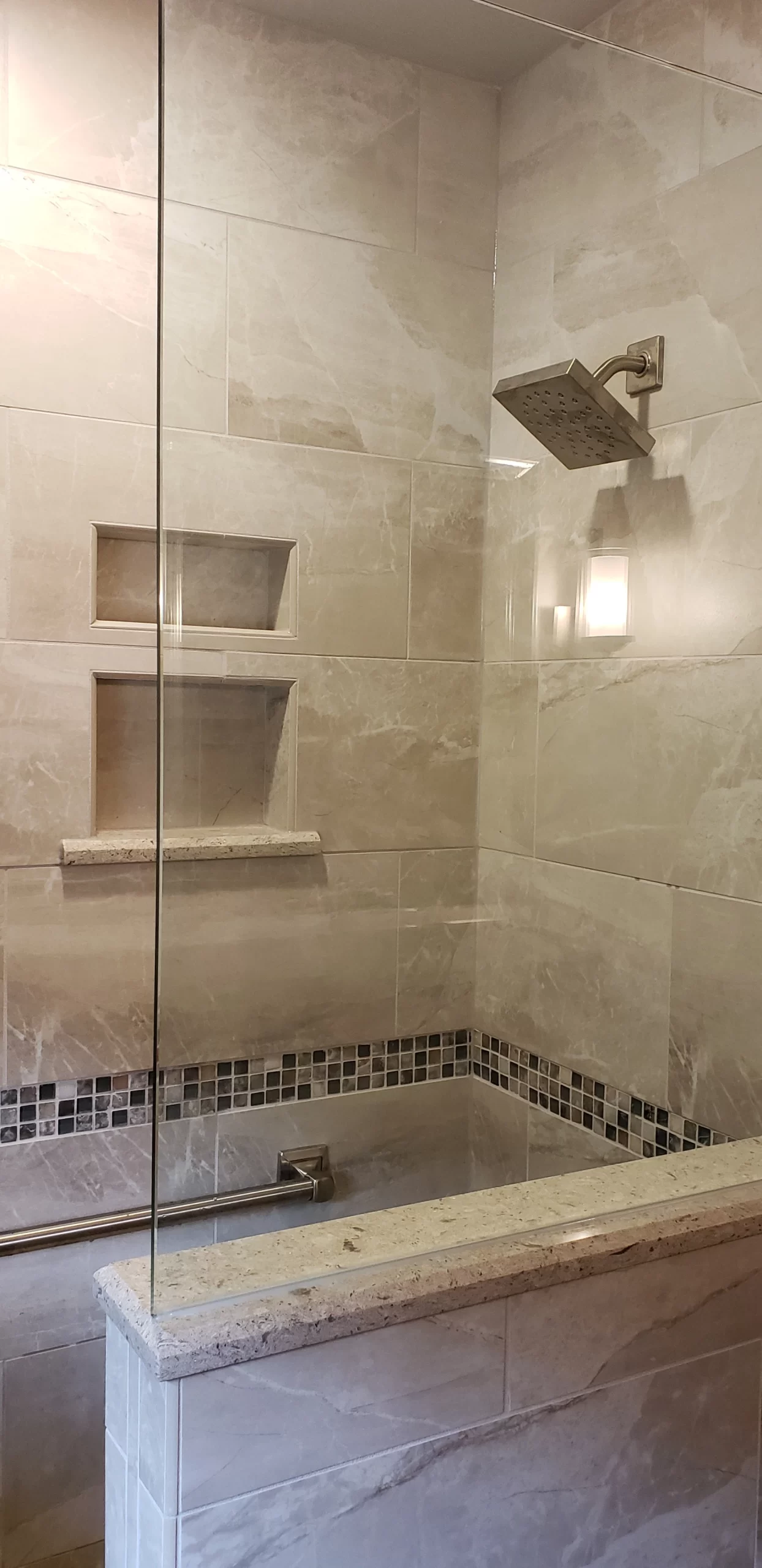 Remodeled bathroom vanity with polished stone countertop and dark wood cabinetry