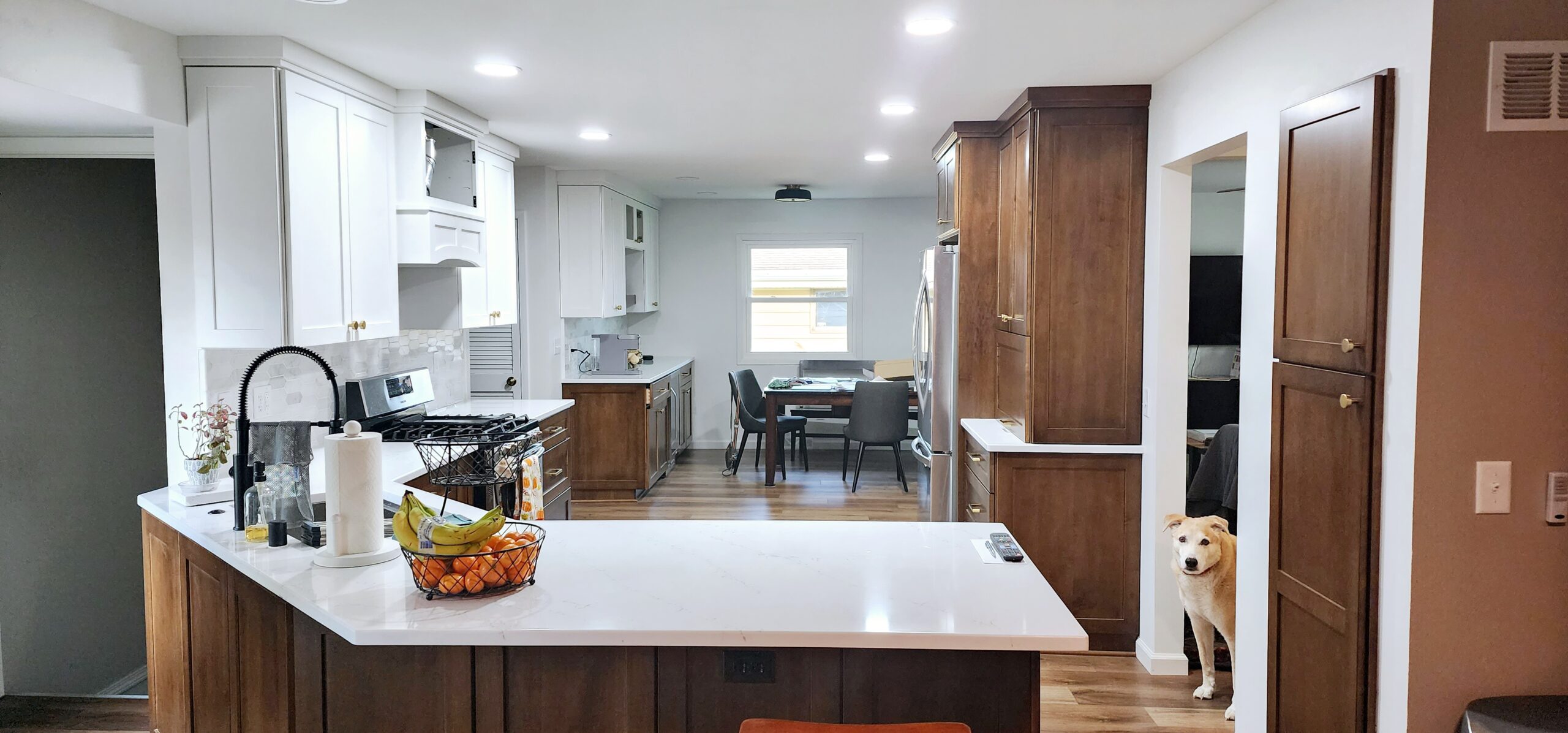 Remodeled kitchen with white upper cabinets, wood lowers and quartz peninsula in a Milwaukee-area home
